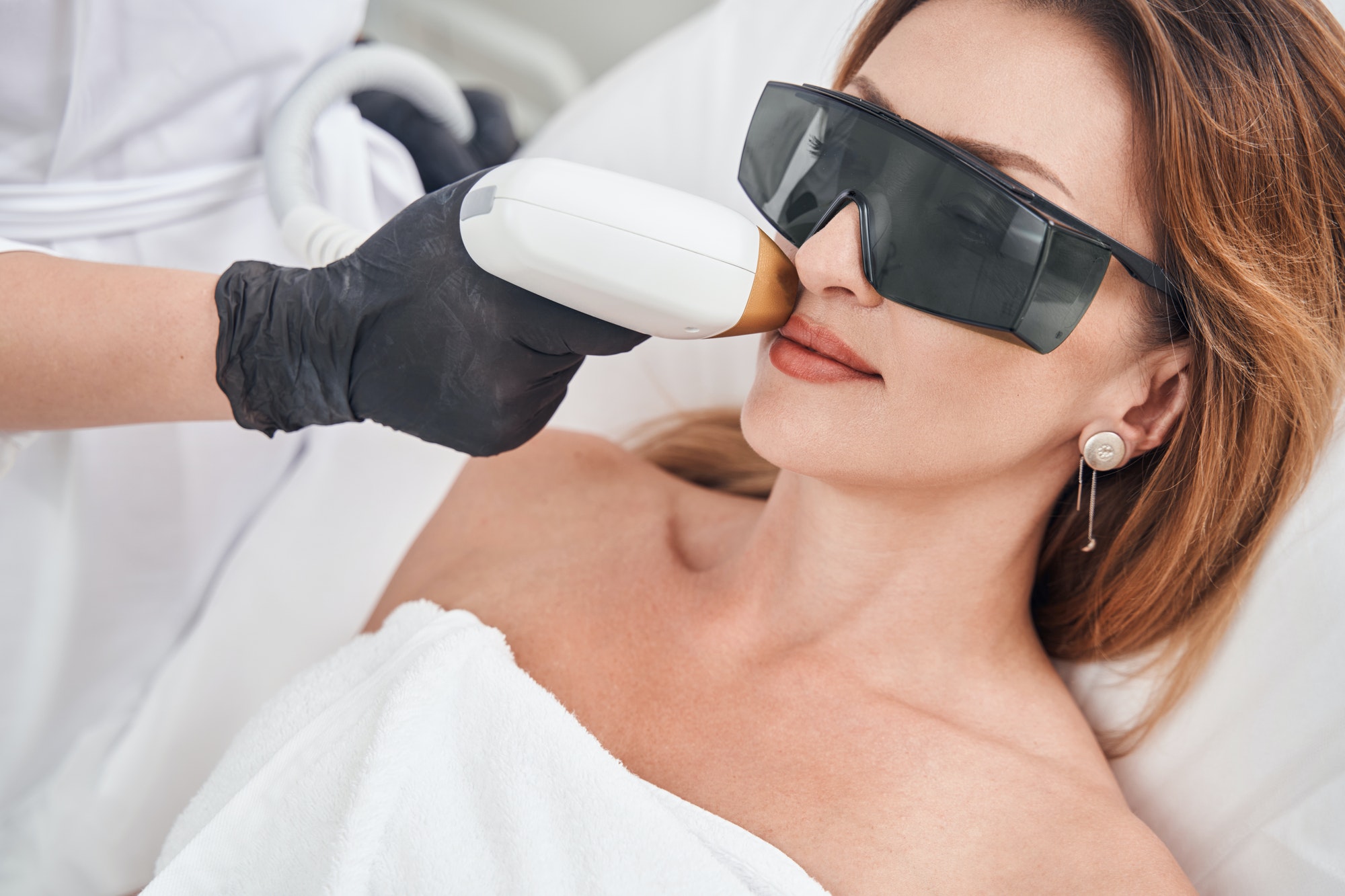 Relaxed pretty woman during face laser epilation